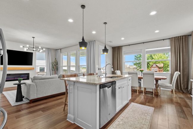 Kitchen with stainless steel appliances, hardwood / wood-style flooring, white cabinets, a center island with sink, and a chandelier | Image 16