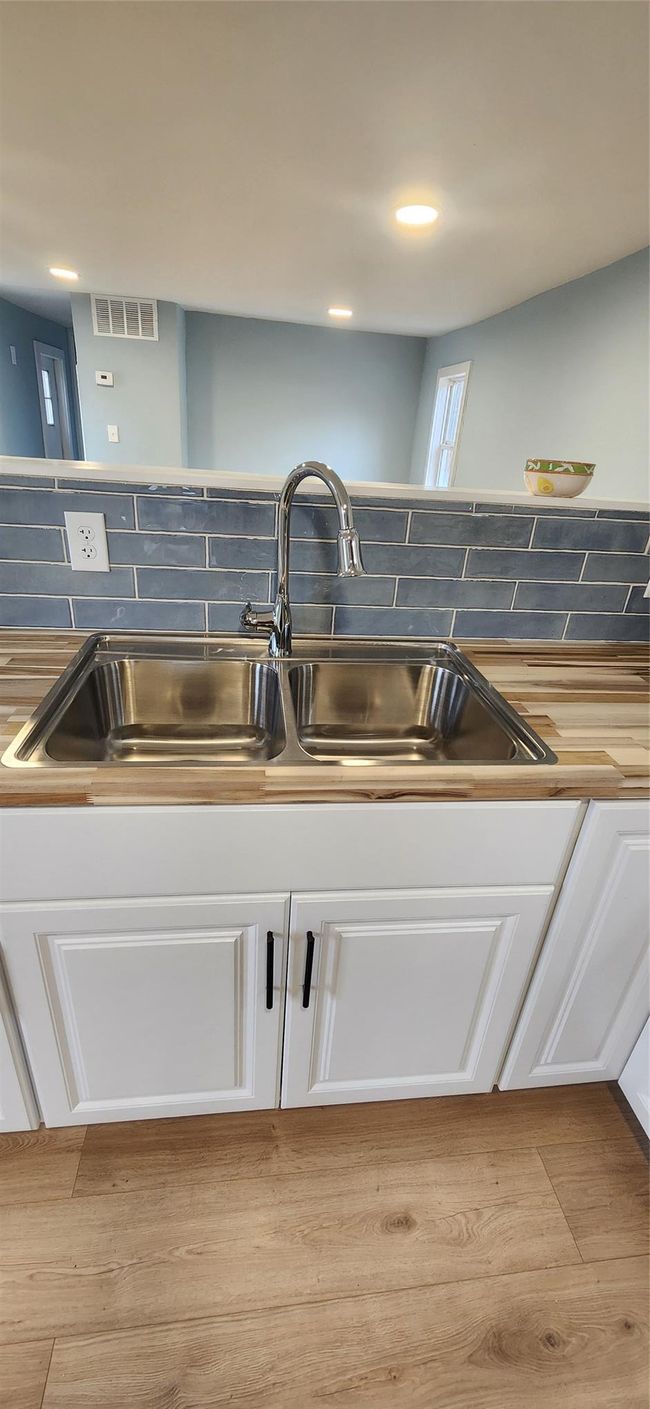 Details featuring wood finished floors, a sink, white cabinetry, and visible vents | Image 4