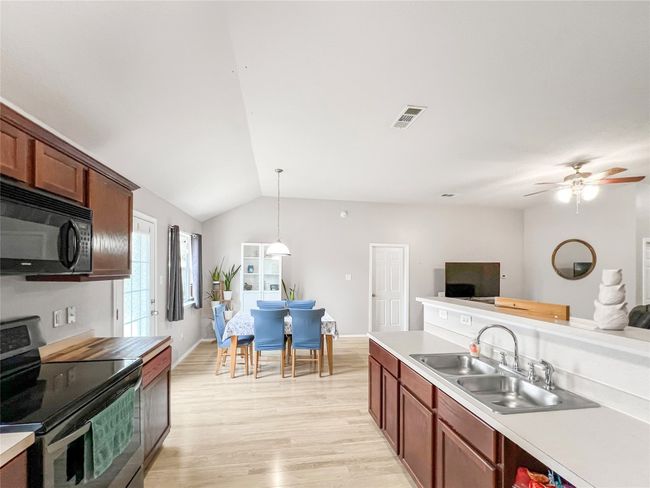 Kitchen featuring black microwave, stainless steel range with electric stovetop, a sink, open floor plan, and lofted ceiling | Image 14