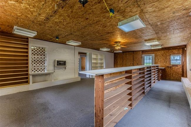 Bar area featuring a ceiling fan, wood walls, and heating unit | Image 48