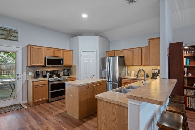 Kitchen featuring appliances with stainless steel finishes, a sink, a center island, dark wood finished floors, and a peninsula | Image 8