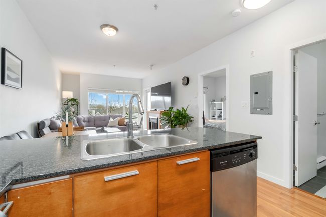 Kitchen featuring light wood-style flooring, stainless steel dishwasher, open floor plan, a sink, and electric panel | Image 18