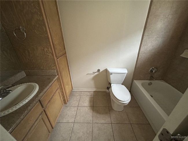 Full bath featuring tile patterned floors, toilet, vanity, baseboards, and tub / shower combination | Image 9
