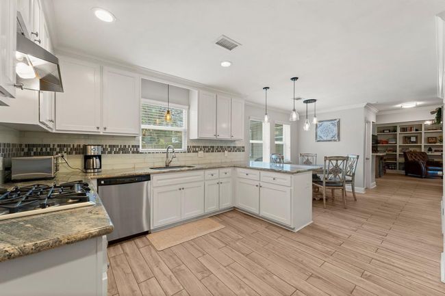 The bright, open-concept kitchen flows seamlessly into a dining area creating a warm and inviting space. | Image 11