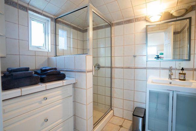 Bathroom with a shower stall, tile walls, tile patterned flooring, and vanity | Image 25