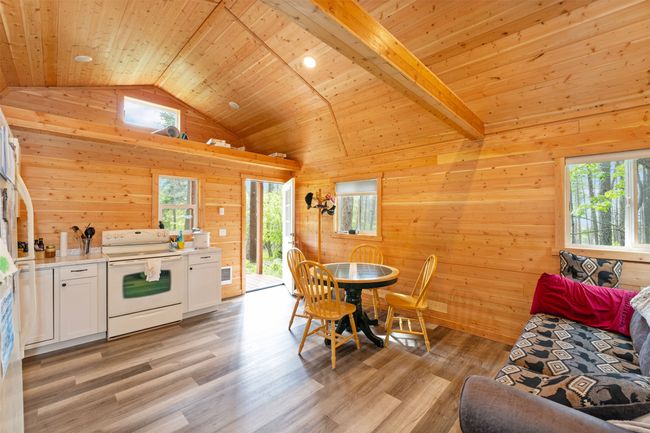 Dining room with lofted ceiling, wooden ceiling, wooden walls, and light wood finished floors | Image 12