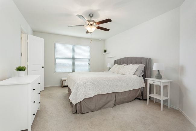 This bright and open primary bedroom has tall ceilings and a ceiling fan! | Image 14