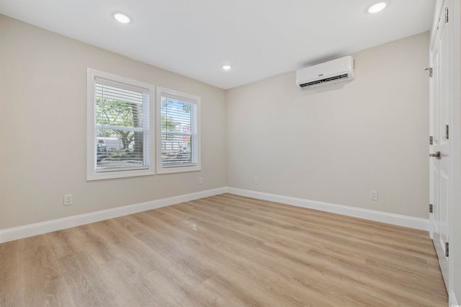 Empty room featuring a wall unit AC, light wood-style flooring, baseboards, and recessed lighting | Image 27