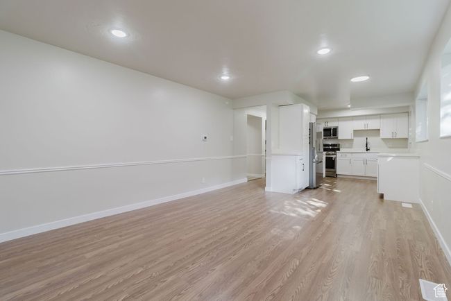 Unfurnished living room with a sink, visible vents, recessed lighting, baseboards, and light wood-style floors | Image 8