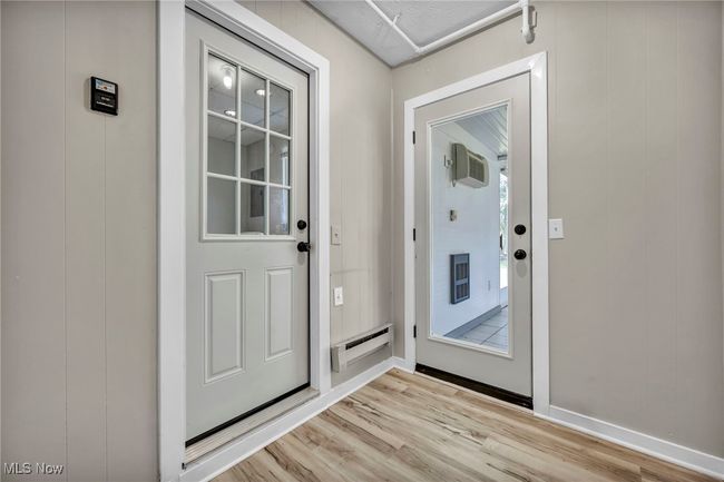 Doorway to outside with light wood-style flooring, a wall mounted AC, and a baseboard radiator | Image 32