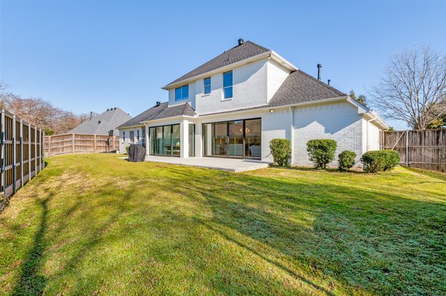 Rear view of house with brick siding, a fenced backyard, roof with shingles, and a patio area | Image 34