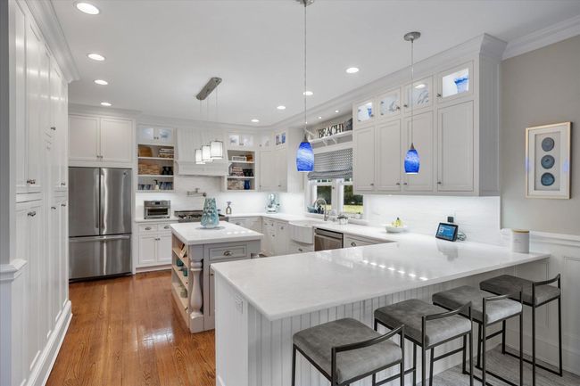 Kitchen with dark wood-style floors, a peninsula, appliances with stainless steel finishes, and open shelves | Image 11
