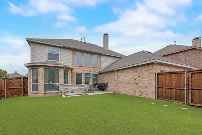 Rear view of property with brick siding, a gate, a patio, a chimney, and a shingled roof | Image 30