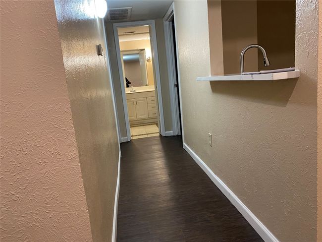 Hallway with baseboards, visible vents, dark wood-style floors, and a textured wall | Image 10