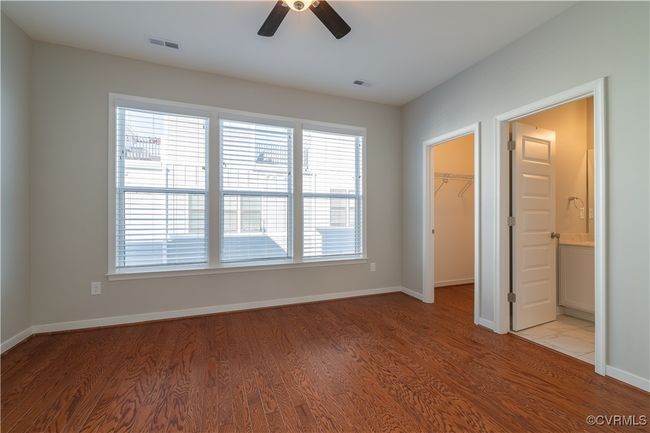 Unfurnished bedroom with connected bathroom, light hardwood / wood-style flooring, ceiling fan, and a walk in closet | Image 8