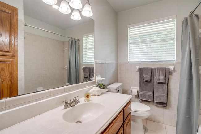 Full bathroom featuring tile walls, vanity, a chandelier, tile patterned flooring, and a shower with shower curtain | Image 31