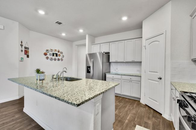 Kitchen featuring stainless steel appliances, a sink, light stone counters, dark wood-style floors, and recessed lighting | Image 9