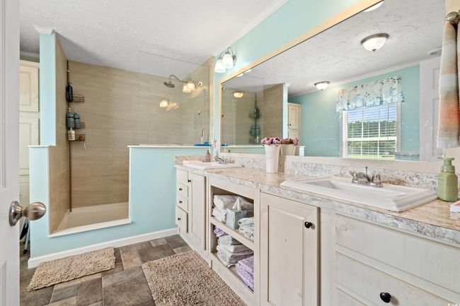 Full bathroom with walk in shower, double vanity, a textured ceiling, stone finish flooring, and ornamental molding | Image 17