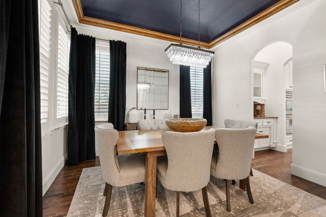 Formal Dining space with plenty of natural light, wood shutters, a stunning chandelier, cove lighting, solid wood flooring, 6 inch baseboards and handsome crown moldings. | Image 7