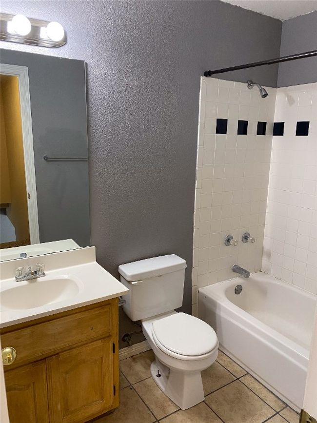 Full bathroom with a textured wall, tile patterned flooring, vanity, toilet, and bathing tub / shower combination | Image 18