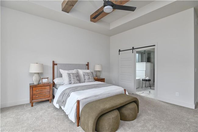 Bedroom featuring beam ceiling, carpet floors, a barn door, and ceiling fan | Image 23