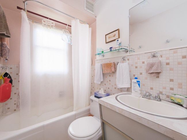 Full bath featuring tile walls, shower / bathtub combination with curtain, toilet, vanity, and a wainscoted wall | Image 15