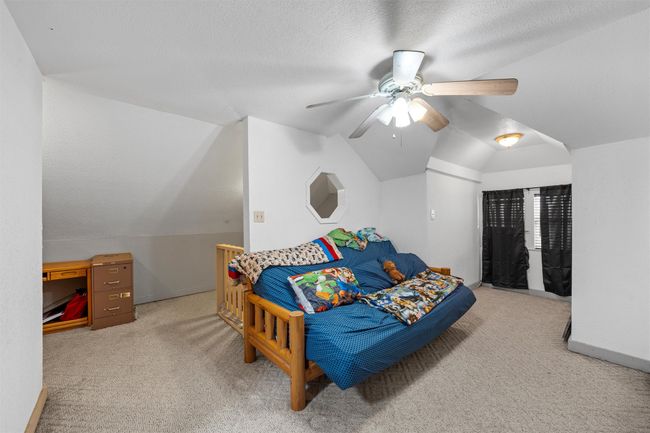 Bedroom featuring a ceiling fan, a textured ceiling, lofted ceiling, baseboards, and carpet | Image 16