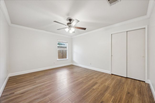 Oversized secondary bedroom with large windows, crown molding, ceiling fan, and closet with sliding doors | Image 21