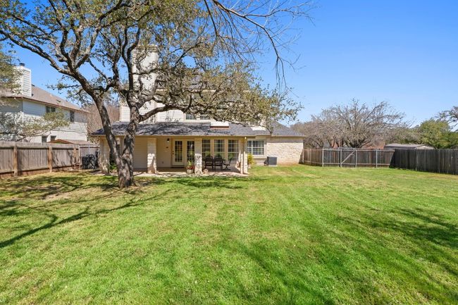 Rear view of house with a fenced backyard, a patio, and a yard | Image 37