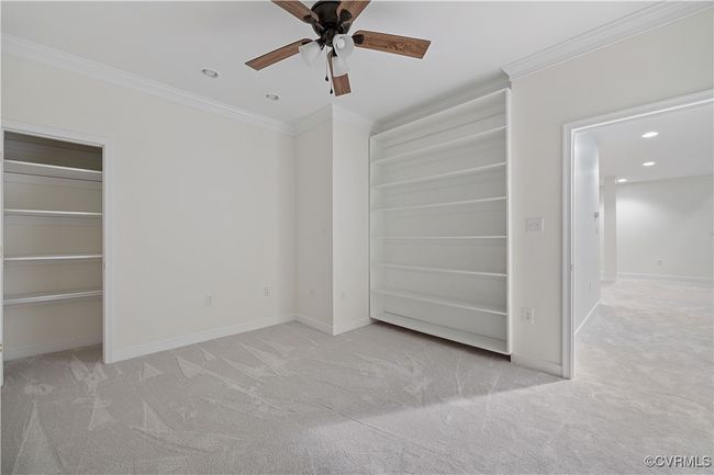 Basement office space with recessed lighting, a ceiling fan, crown molding, and carpet flooring, built-in bookcases | Image 49