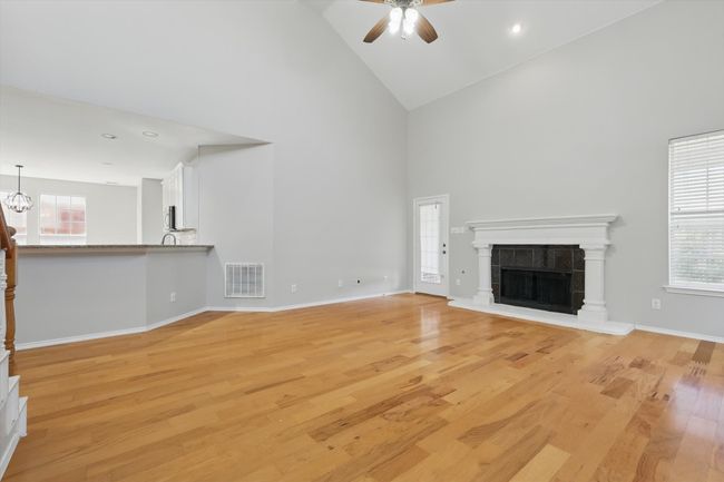 Unfurnished living room with ceiling fan, high vaulted ceiling, light wood finished floors, baseboards, and a tiled fireplace | Image 7