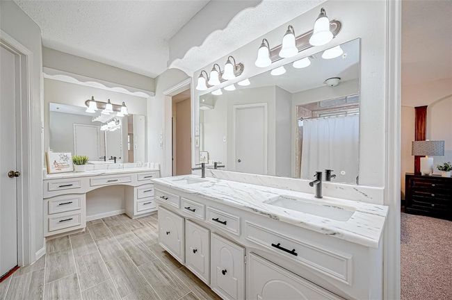 Primary bathroom with dual sinks, elegant quartzite countertops, white cabinetry, new fixtures and tile. Desisgned to provide a luxurious and comfortable personal retreat with 2 large walk-in closets. | Image 29