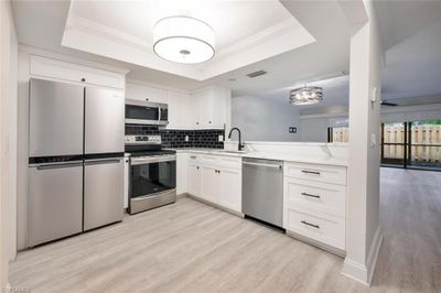 Kitchen with a raised ceiling, white cabinetry, stainless steel appliances, and sink | Image 2