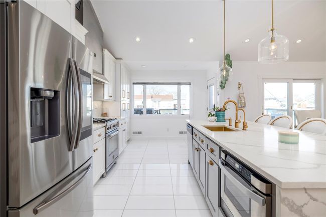 Kitchen with a center island with sink, a sink, light tile patterned flooring, white cabinets, and appliances with stainless steel finishes | Image 7