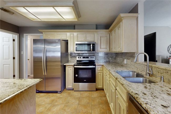 Kitchen featuring appliances with stainless steel finishes, a sink, cream cabinets, and tasteful backsplash | Image 10