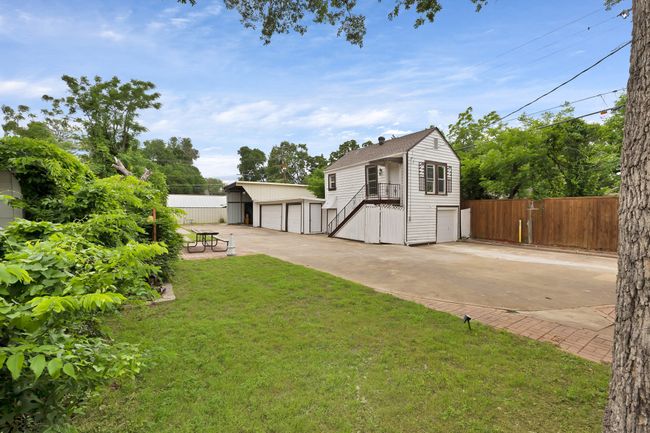 View of yard with fence, a detached garage, 2 two car garages, front one with apartment above with stairs | Image 29