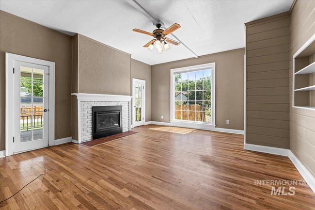 Unfurnished living room featuring a ceiling fan, wood finished floors, and a fireplace | Image 21