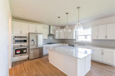 Photo is of the actual home. The Washburn offers a gourmet kitchen with Frigidaire professional appliances, quartz countertops, soft close cabinets, under cabinet lighting and walk in pantry. | Image 2