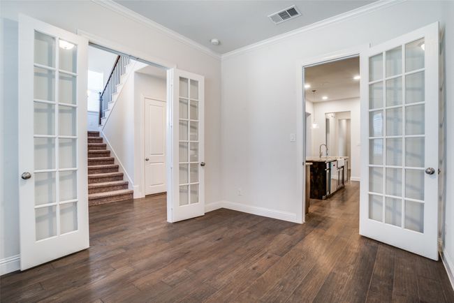 Unfurnished room featuring french doors, dark wood-style flooring, crown molding, and stairway | Image 4