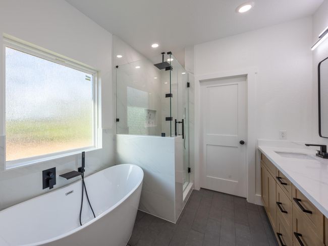 Treat yourself to ultimate relaxation with a freestanding soaking tub, a walk-in frameless glass shower with rainfall showerhead, and timeless tilework throughout. Thoughtfully designed for luxury and comfort. | Image 5