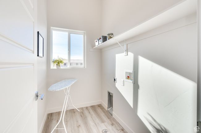 Laundry room featuring hookup for a washing machine, electric dryer hookup, light wood-style flooring, and baseboards | Image 18