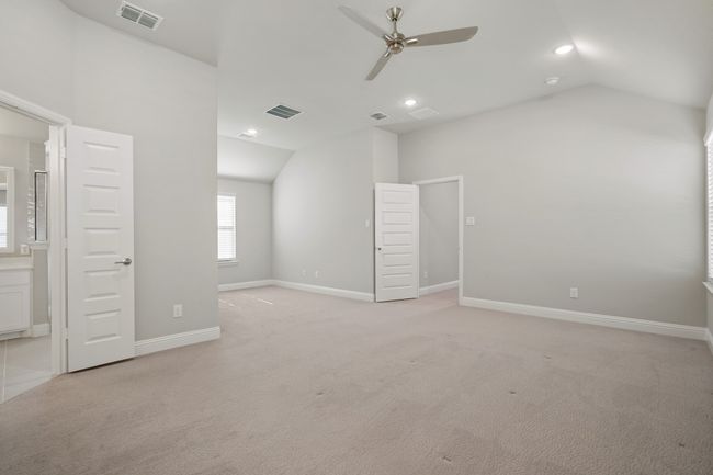 Unfurnished bedroom with baseboards, visible vents, light colored carpet, and lofted ceiling | Image 17