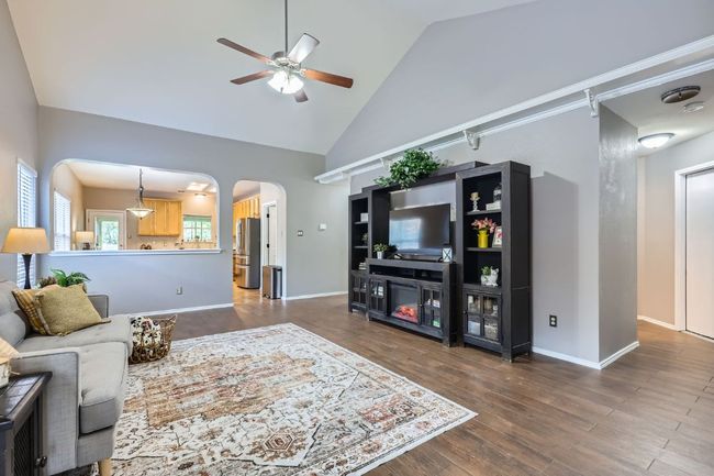 Living area with ceiling fan, arched walkways, high vaulted ceiling, and dark wood finished floors | Image 5