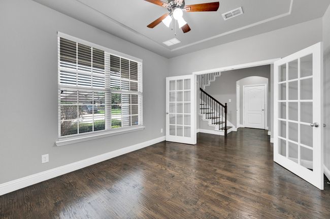 Dedicated office is conveniently located at the front of the home with doors for privacy, wood floors, ceiling fan and window blinds. | Image 5
