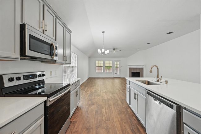 Kitchen with stainless steel appliances, a sink, gray cabinetry, a chandelier, and dark wood finished floors | Image 26