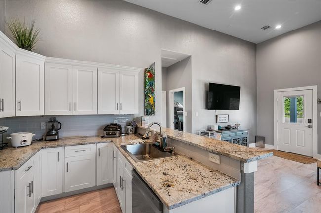 Modern kitchen with sleek granite countertops, ample white cabinetry, and an open layout perfect for entertaining. | Image 5