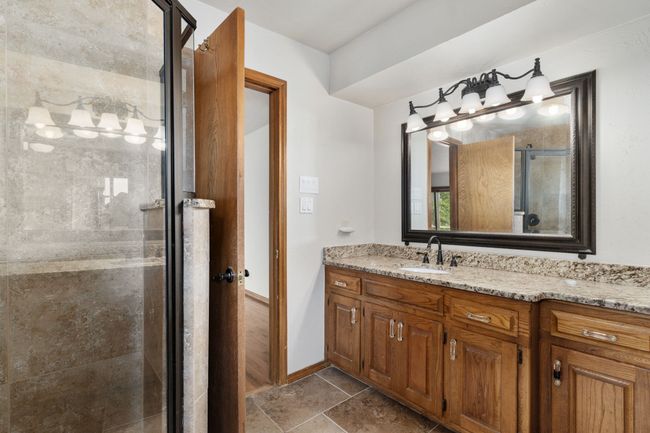 Bathroom featuring baseboards, a shower stall, stone finish floor, and vanity | Image 24