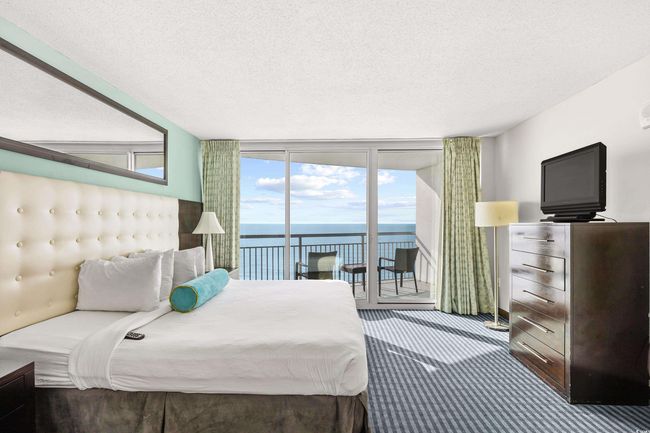 Carpeted bedroom featuring expansive windows, baseboards, access to exterior, and a textured ceiling | Image 20