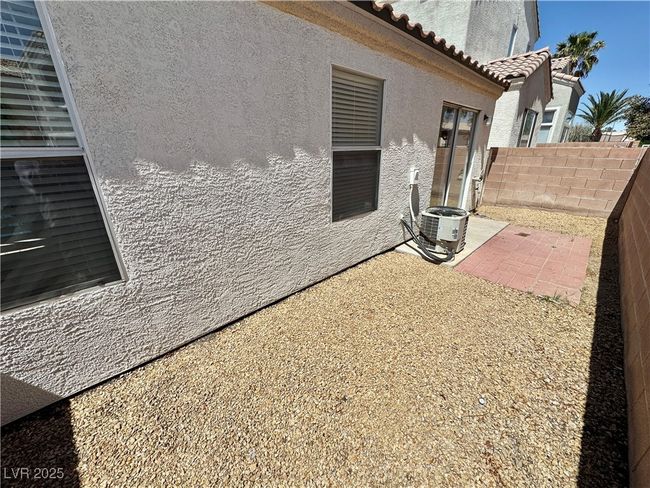 View of side of property featuring a patio area, central air condition unit, a tiled roof, fence, and stucco siding | Image 16