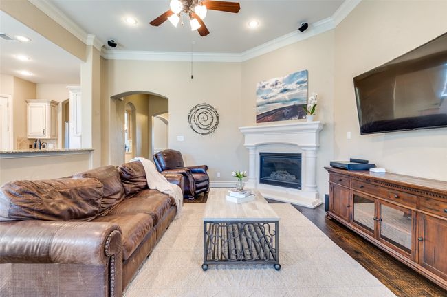 Living room with wood finished floors, arched walkways, ceiling fan, and ornamental molding | Image 8